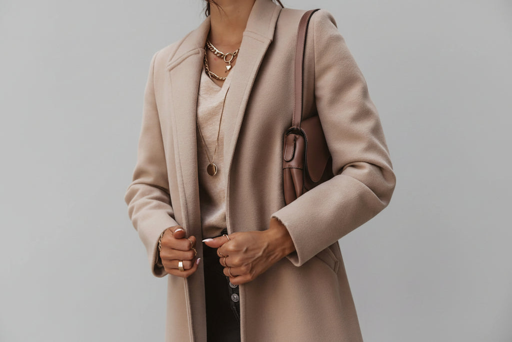 Person wearing a beige coat with a neutral background