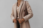 Person wearing a beige coat with a neutral background